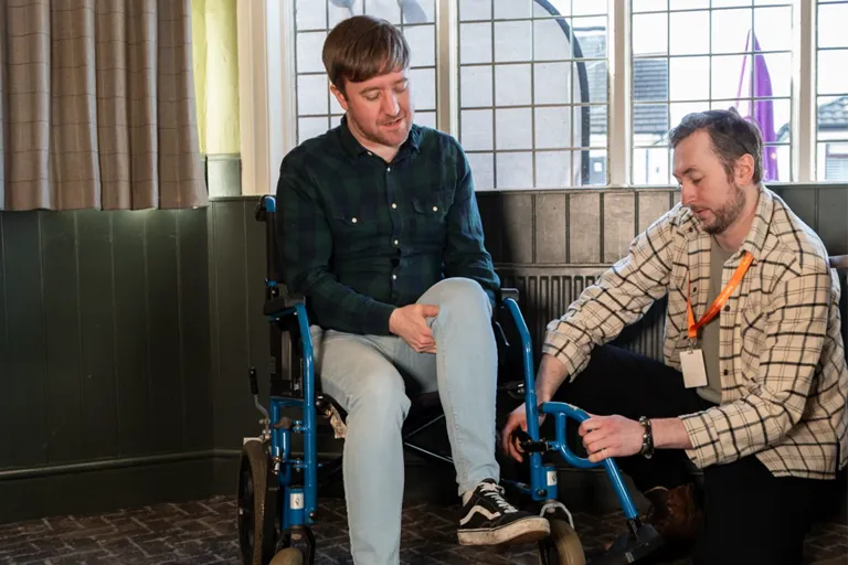 A client using a wheelchair enjoying an open mic night with support from their care team